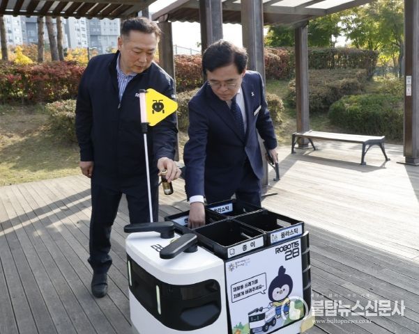 진교훈 서울 강서구청장(오른쪽)이 마곡하늬공원에서 열린 ‘AI 기반 자율주행 로봇서비스 실증 시연회’에서 빈 캔을 수거함에 넣고 있다.